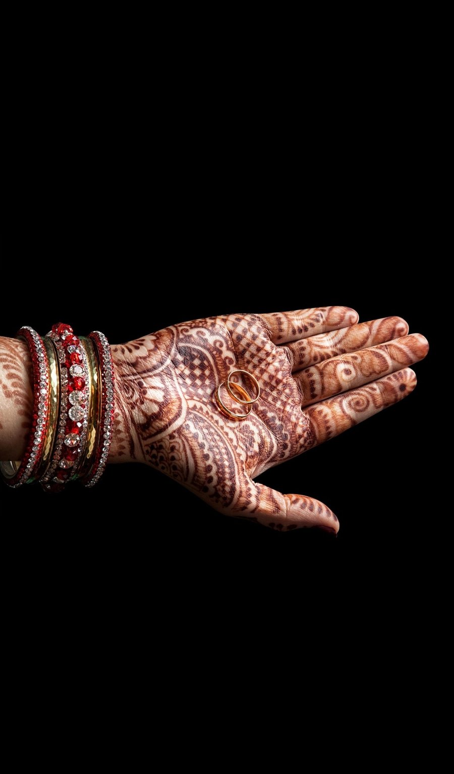 Bridal hand with wedding rings and mehndi design